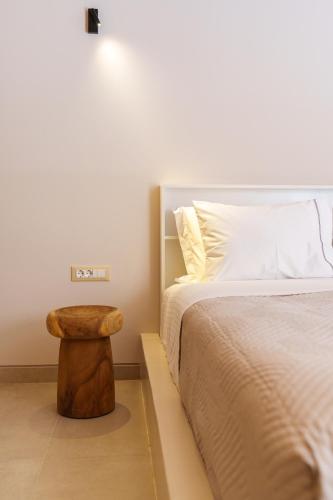 a bedroom with a bed with a wooden stool next to it at Halo Santorini - Living Experience in Fira