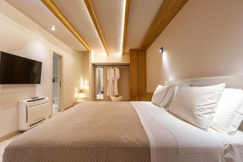 a bedroom with a large bed and a television at Halo Santorini - Living Experience in Fira