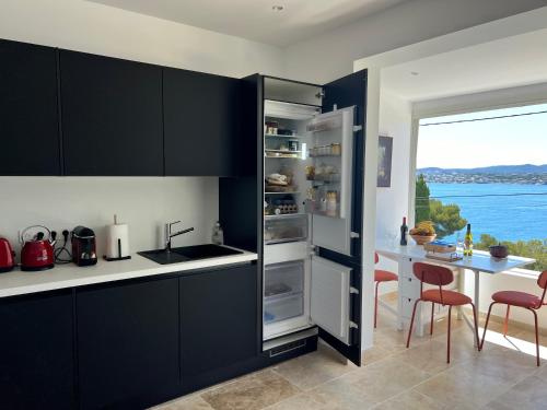 Il comprend une cuisine équipée d'un réfrigérateur et d'une table avec des chaises. dans l'établissement Breathtaking Mediterranean Views from Renovated Cosy Nest, Walk to Portissol Beach and Port, à Sanary-sur-Mer