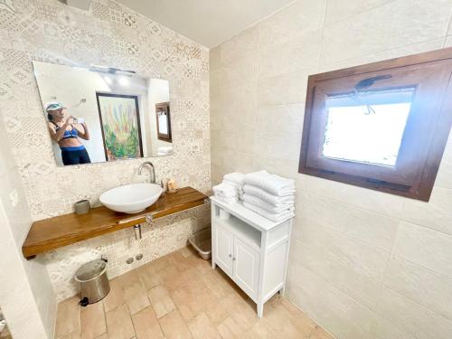 a woman taking a picture of a bathroom with a sink at Fab villa with fenced pool, huge grounds, meditation park, child activity park in Limiti