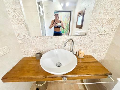 a woman taking a picture of a sink in a bathroom at Fab villa with fenced pool, huge grounds, meditation park, child activity park in Limiti