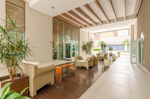 an open living room with furniture and plants at Lifespace Curitiba - Apartamentos UROOMS in Curitiba