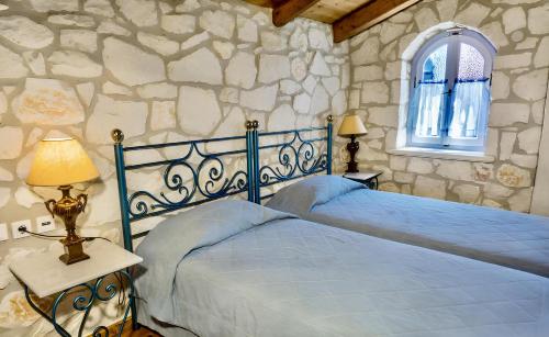 a bedroom with two beds and a stone wall at Aresti Mountain Resort in Agios Leon