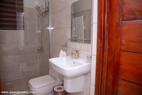 Un baño con lavabo, ducha e inodoro. en Cozy 1 bed Apartment with AC and Kitchenette, en Accra