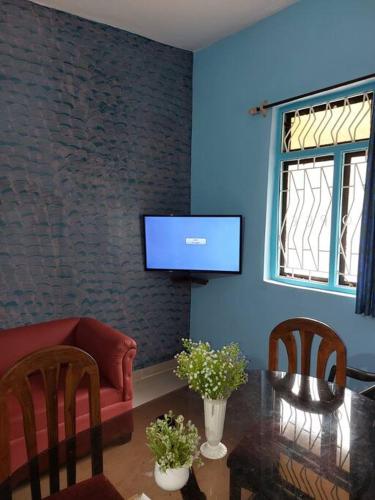 Una sala de estar con un sofá, una mesa y un televisor. en Oliver's Goa Guesthouse, en Carmona