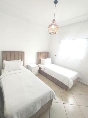 マルティルにあるJannat Luxury homeの白い部屋(ベッド2台、シャンデリア付)