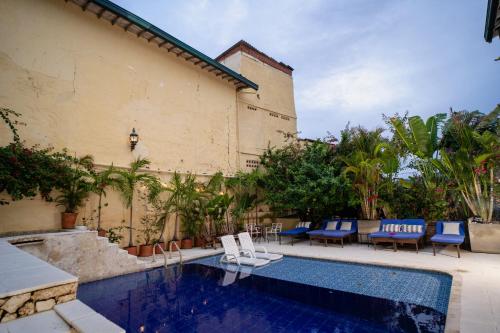 a swimming pool with blue chairs and a building at Casa Al Alma in Santa Fe de Antioquia