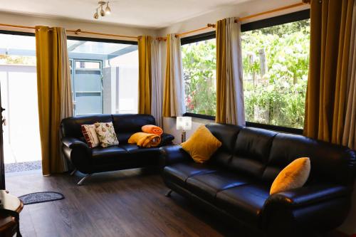 a living room with a black leather couch and windows at Marialina, By OP in São Vicente