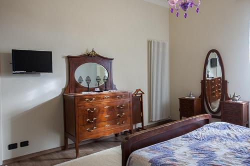 een slaapkamer met een dressoir, een spiegel en een bed bij Locanda Alla Posta in Cavaso del Tomba