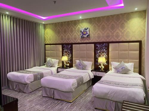 three beds in a room with a purple lighting at ابراج الجود للشقق المخدومة in Al Ḩawīyah