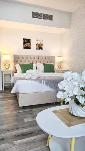 a white bedroom with two beds and a table at Luxury Beach Studio in Ras al Khaimah