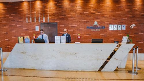 two men are standing behind a large table in a building at Nobile Suites Monumental in Brasilia