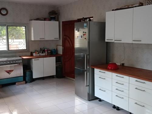 a kitchen with white cabinets and a stainless steel refrigerator at Berlin in Ziguinchor