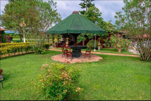 a gazebo with a table and chairs in a yard at Finca Hotel El Ocaso in Quimbaya