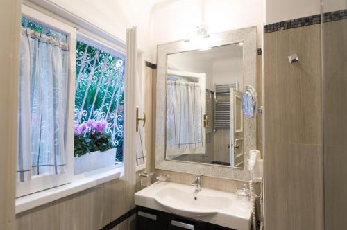een badkamer met een wastafel, een spiegel en een raam bij Margutta's Garden in Rome