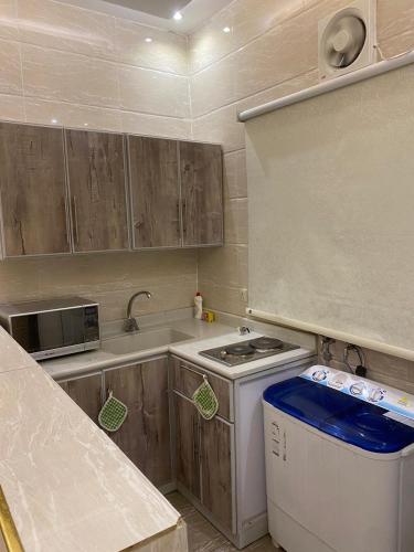 a small kitchen with a stove and a sink at ابراج الجود للشقق المخدومة in Al Ḩawīyah