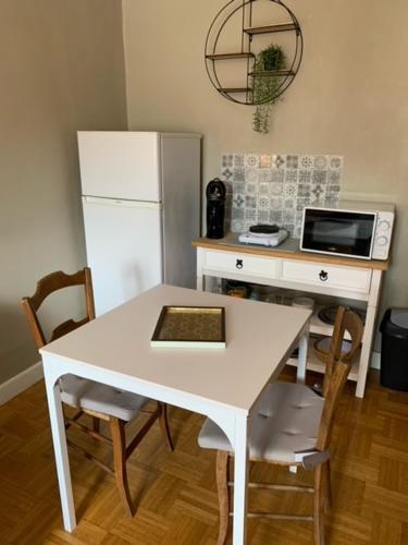 Il comprend une cuisine équipée d'une table blanche et d'un réfrigérateur blanc. dans l'établissement Chambre calme au cœur d’Ussel, à Ussel