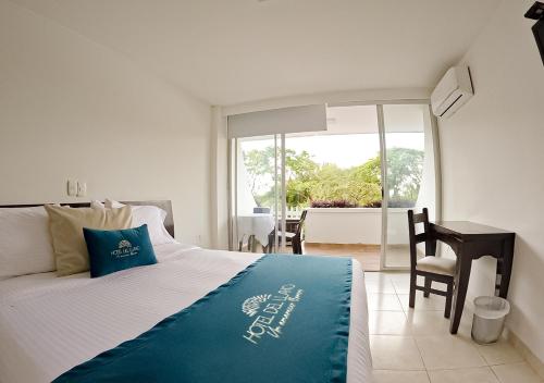 a bedroom with a bed and a desk and a window at Hotel del Llano in Villavicencio