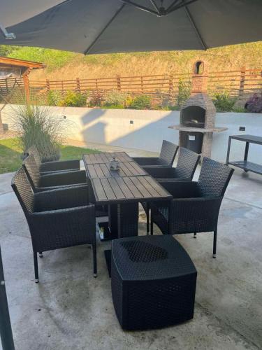 a wooden table with chairs and a grill in a patio at Apartman Maslina in Kosjerić