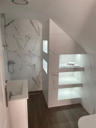 a white bathroom with a shower and a sink at Apartman Maslina in Kosjerić