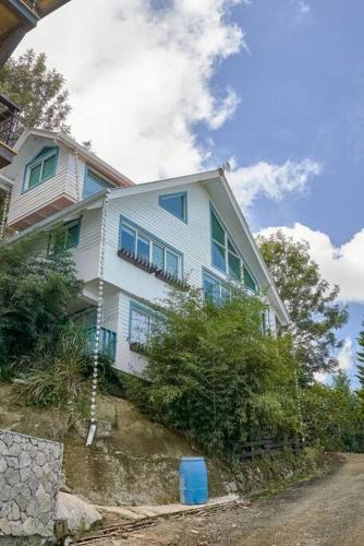 a white house with blue windows on a hill at New-CasitaDeLasFlores-View-Wifi-Jacuzzi-Jarabacoa in Jarabacoa