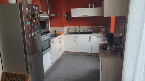 une cuisine avec des armoires blanches et un réfrigérateur noir dans l'établissement Jardins AQUITAINE, à Nîmes