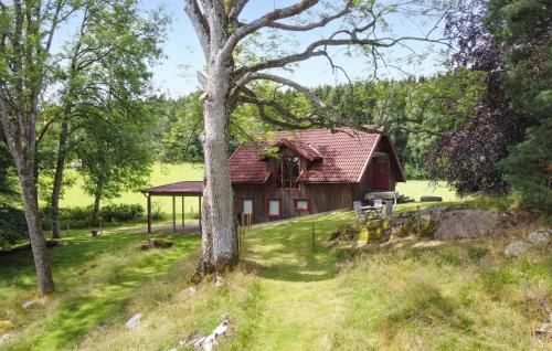 a red barn in a field with a tree at 1 Bedroom Awesome Home In Västerlanda in Västerlanda