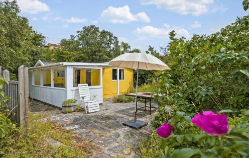 a yellow tiny house with a table and an umbrella at 1 Bedroom Gorgeous Home In Aakirkeby in Åkirkeby