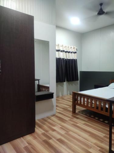 a bedroom with a bed and a wooden floor at Vidhara Rooms in Trivandrum