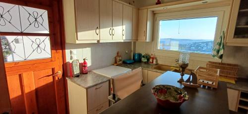a kitchen with white cabinets and a large window at MarGeo View House in Mpatsi, Andros in Batsi