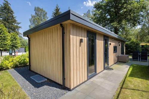 a large wooden building in a garden at Modern huisje op de Veluwe in Epe