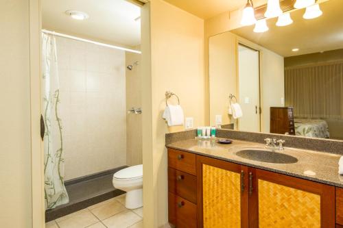 a bathroom with a sink and a toilet and a mirror at Castle Kama'ole Sands in Wailea