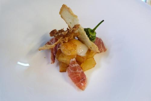 a plate of food with bacon and other foods at La Mira de Gredos in Hoyos del Espino