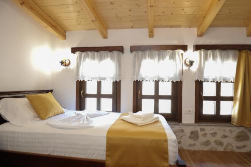 a bedroom with a bed with two windows at The House of Dollma , Inside Kruja Castle in Krujë