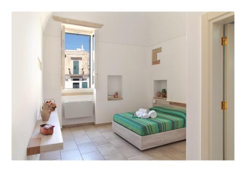 a white bedroom with a bed and a window at Manipinta B&B in Corigliano dʼOtranto