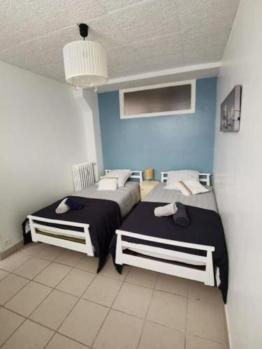 une chambre avec deux lits et un mur bleu dans l'établissement Appartement 2 chambres proche plage, à Boulogne-sur-Mer