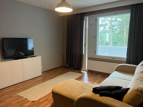 a living room with a couch and a large window at Apartment Mäyränkatu in Kokkola