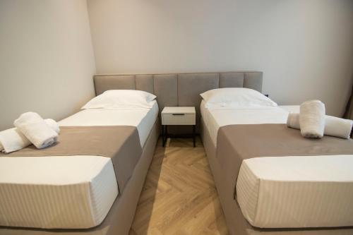 two beds in a room with white walls at Mina Luxury Rooms in Tirana