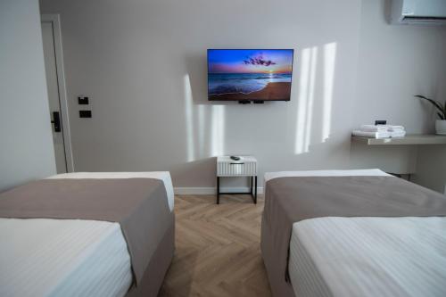 two beds in a room with a tv on the wall at Mina Luxury Rooms in Tirana
