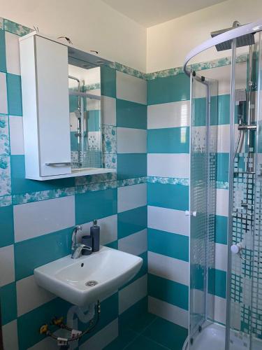 a blue and white bathroom with a sink and shower at La Luca in Maliuc