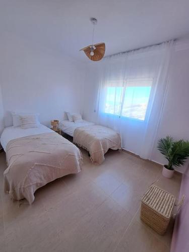 a white room with two beds and a window at Tanger, Vue Mer Panoramique in Noûnouech