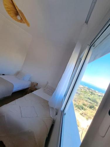 a bedroom with a view of the ocean from a window at Tanger, Vue Mer Panoramique in Noûnouech