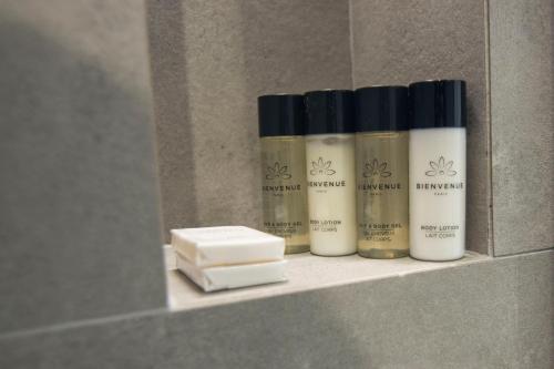 a row of four bottles oficating cosmetics sitting on a shelf at Mina Luxury Rooms in Tirana