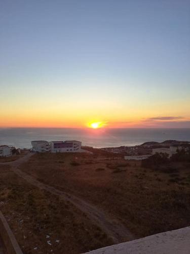 a sunset over a field with a dirt road at Tanger, Vue Mer Panoramique in Noûnouech