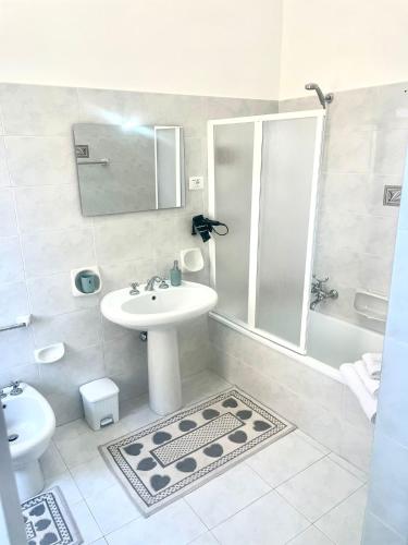 a white bathroom with a sink and a shower at LA CASTELLANA Apartments in Carini