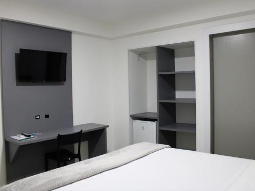 a bedroom with a bed and a desk and a television at Hotel Sagres Praia in Balneário Camboriú
