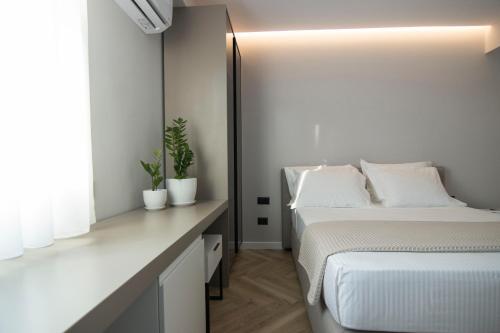 a white bedroom with two beds and a desk at Mina Luxury Rooms in Tirana