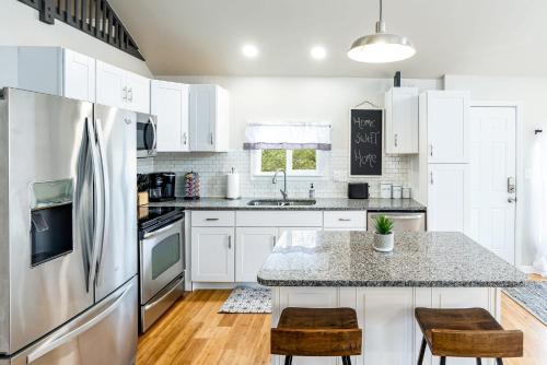 a kitchen with white cabinets and a stainless steel refrigerator at Loft Cabin w, Hot Tub, Fire Pit, Huge Deck & WiFi! in Hedgesville