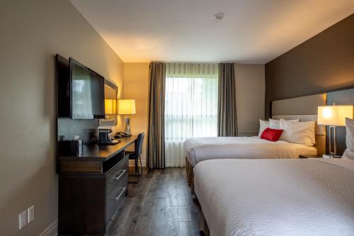 a hotel room with two beds and a flat screen tv at Ramada by Wyndham Ottawa On The Rideau in Ottawa
