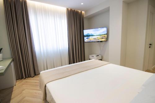 a bedroom with a white bed and a flat screen tv at Mina Luxury Rooms in Tirana